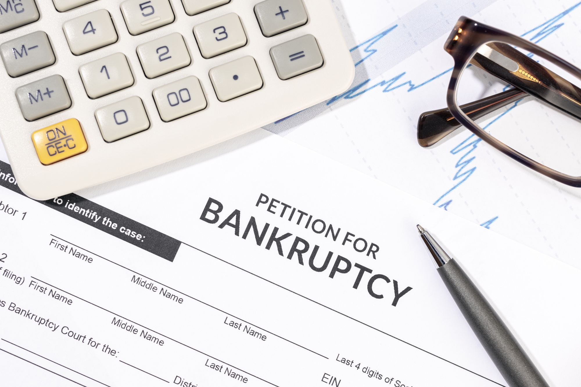 Bankruptcy form, calculator and pen on desk