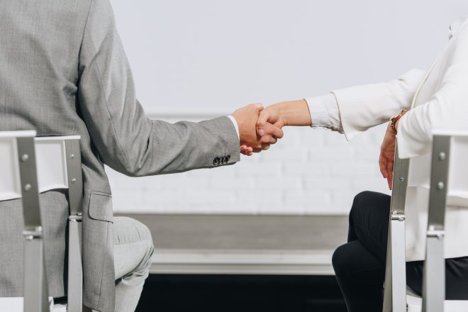 cropped image of businessman and businesswoman shaking hands during business training in hub