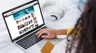 cropped image of woman holding credit card and using laptop with amazon  on screen