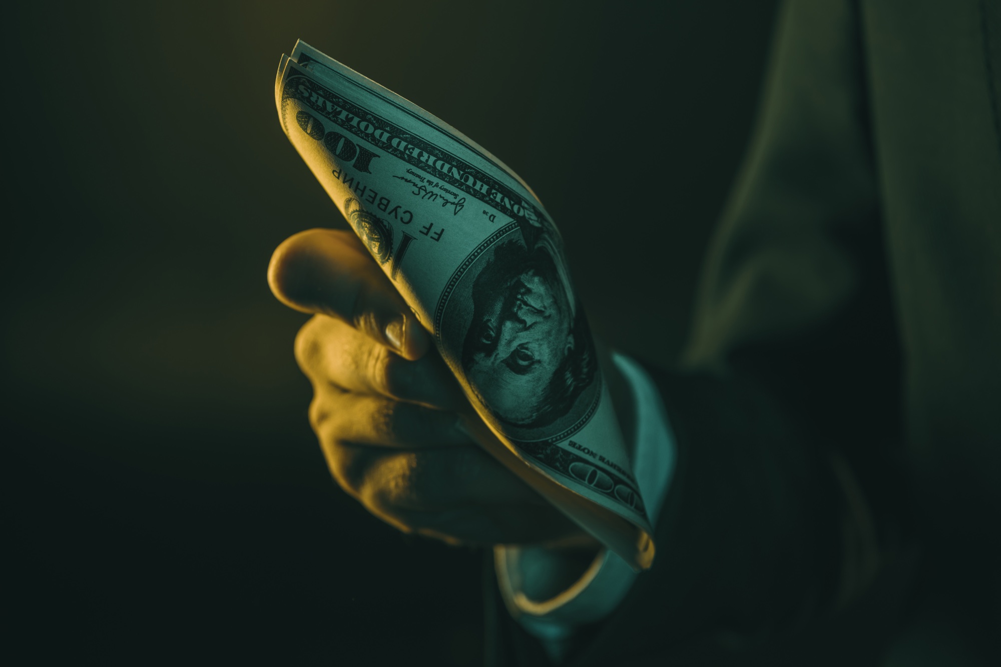cropped shot of man in suit holding us dollar banknotes