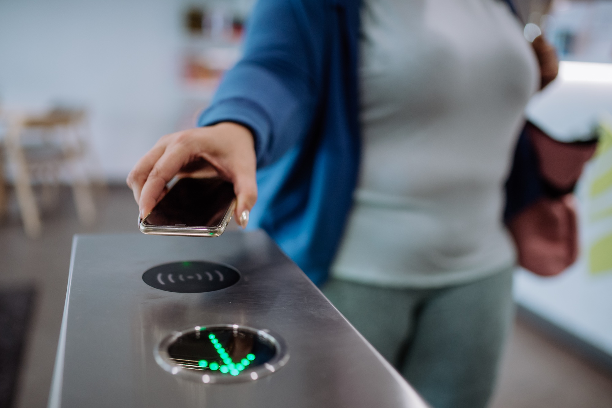 Female hand using smartphone to open automatic gate machine in gym