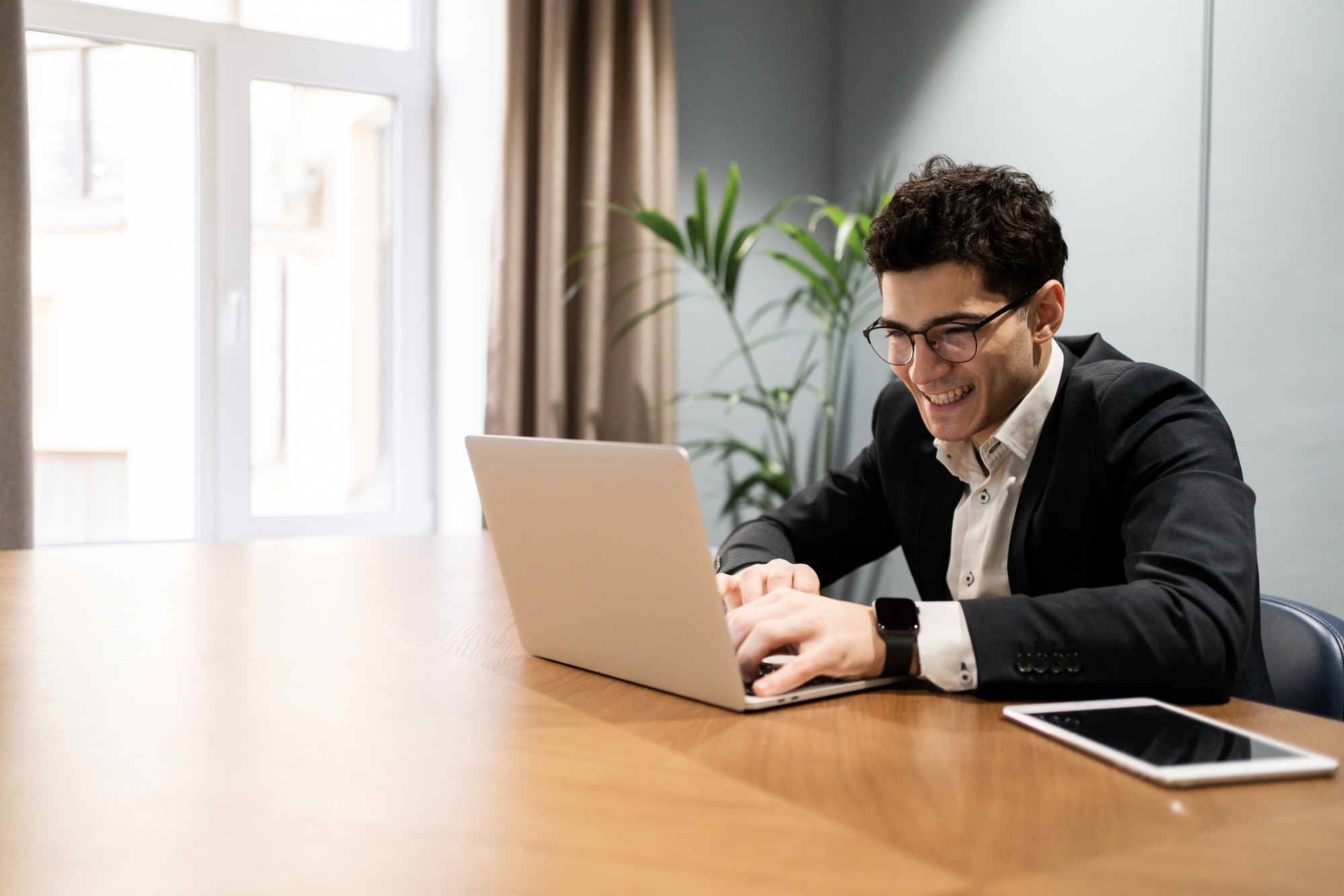 male manager works in the office in a business suit uses a laptop writes a letter to a client